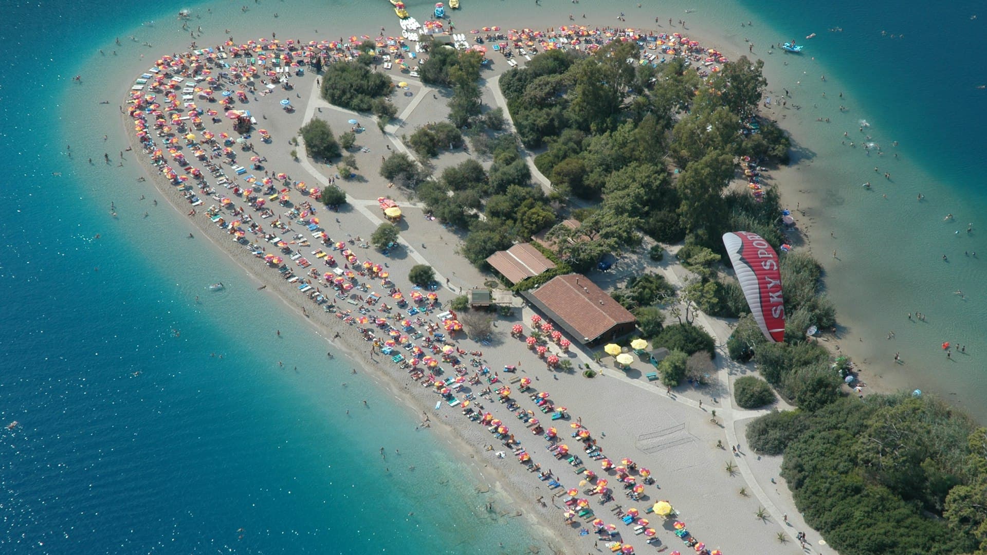Paragliders flying over Ölüdeniz Blue Lagoon with turquoise water and mountains